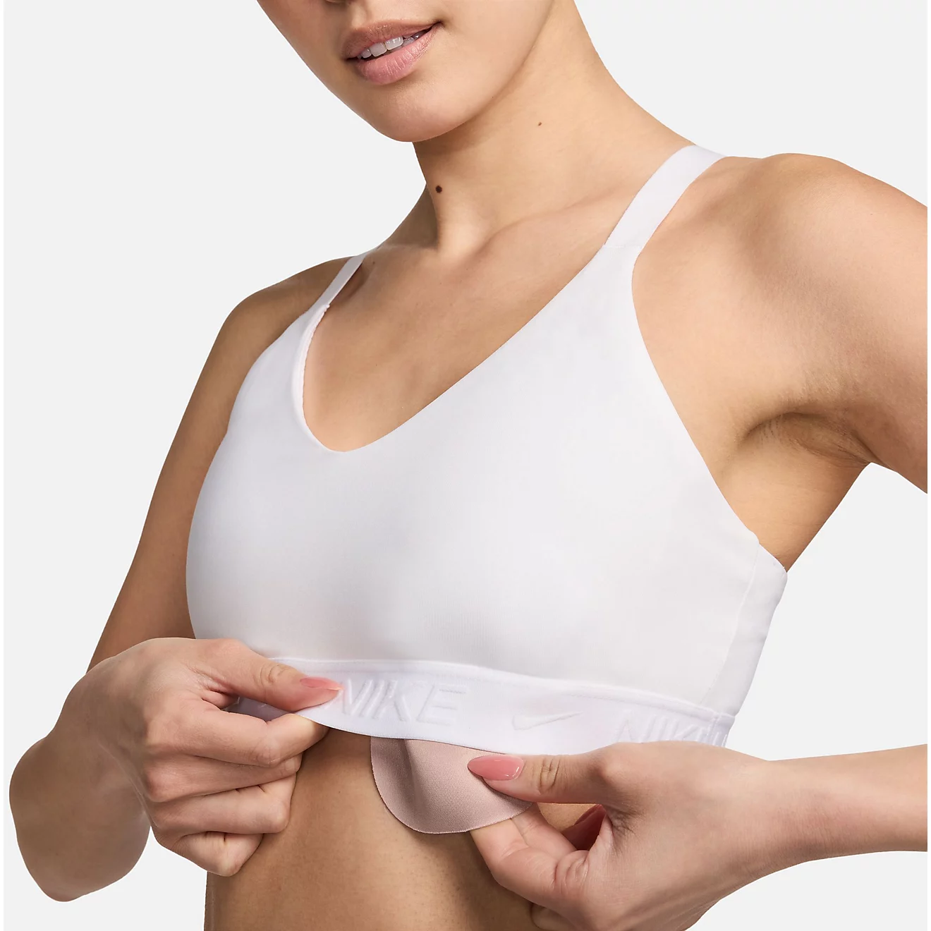 Woman wearing Nike Women’s Dri-FIT Indy medium support sports bra in white with modern athleisure workout outfit